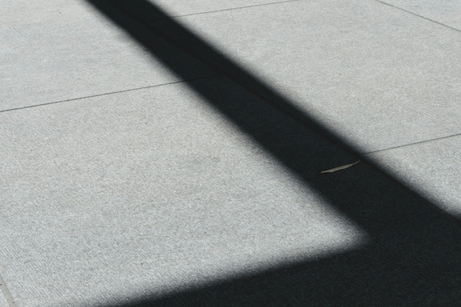 Photo of ground with strong shadow silhouette of a pillar