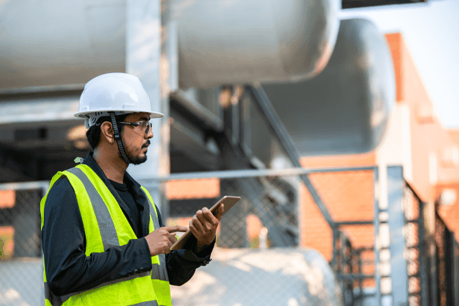 engineer holding ipad and taking down notes at production site